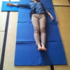 Femme allongée sur un tatami portable bleu déplié au sol – surface de shiatsu légère et compacte tatamiportable.com
